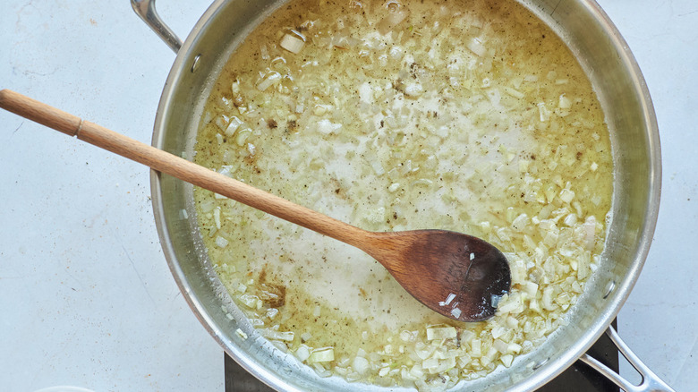 stirring wine and shallots in skillet