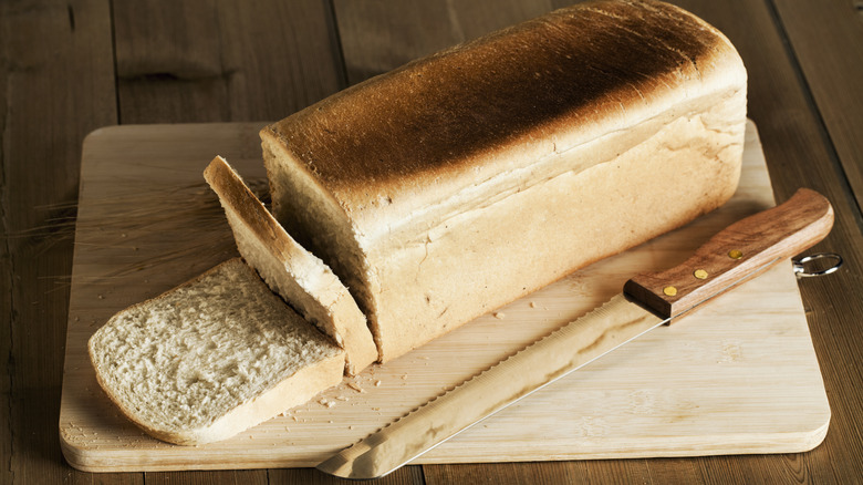 Loaf of white sandwich bread with knife and two slices
