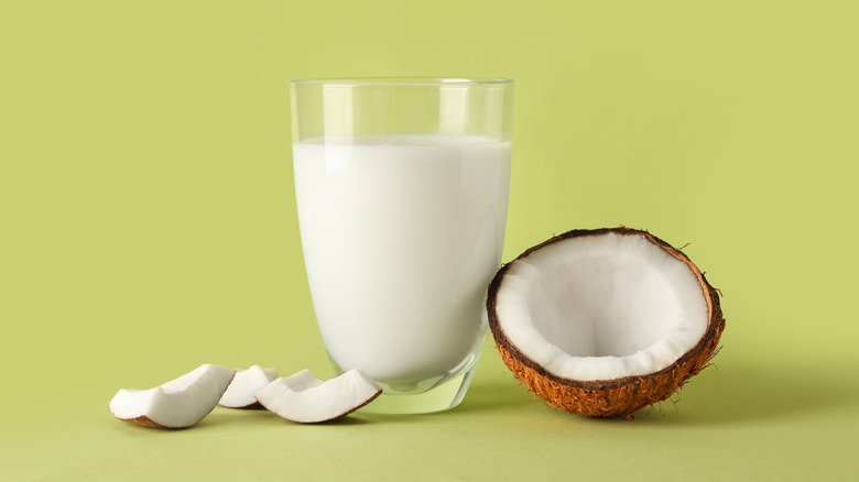 Glass of coconut milk on green background