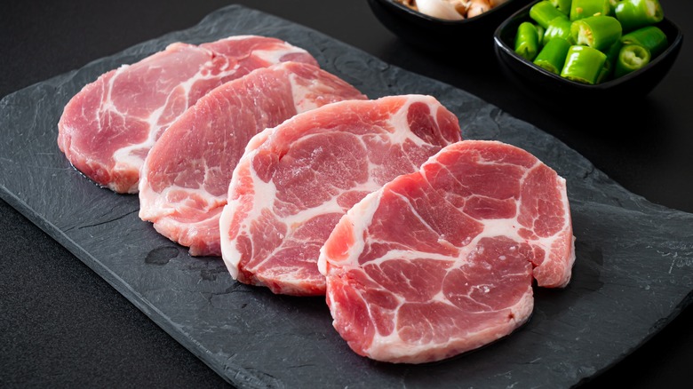 four raw slices of pork neck