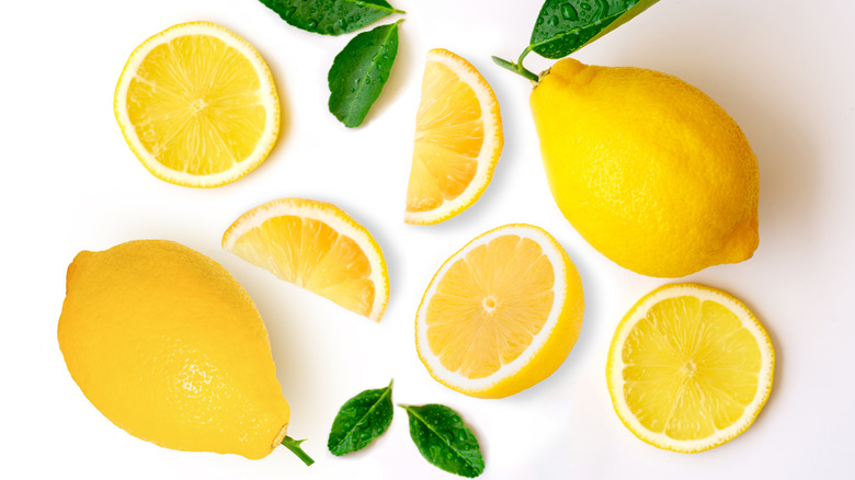 sliced and whole lemons on a white background