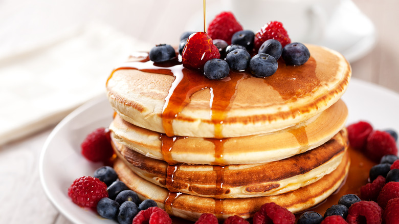 pancakes covered with berries and maple syrup