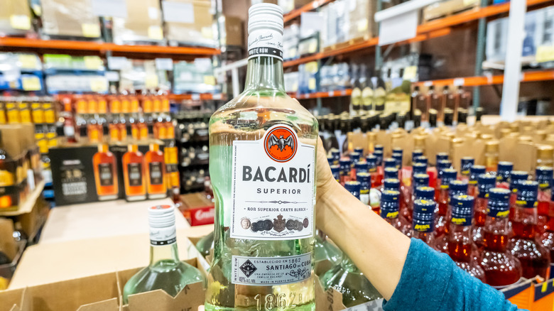 a large bottle of Bacardi Superior being held up in a store