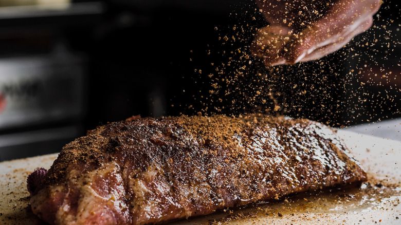 Raw steak being seasoned