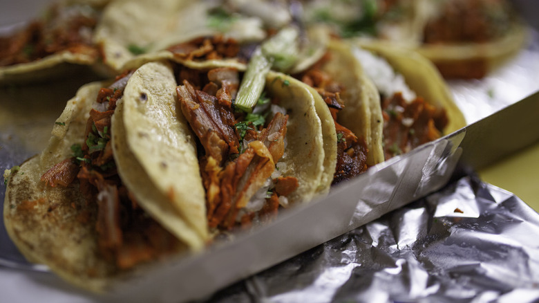 Al Pastor taco's on a silver tray with foil