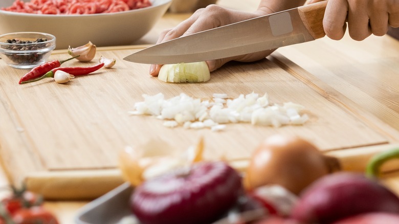 Chopping fresh onion on board