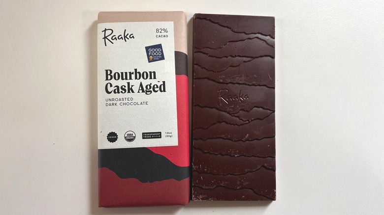 Bar of Raaka Bourbon Cask Aged chocolate next to package on white table
