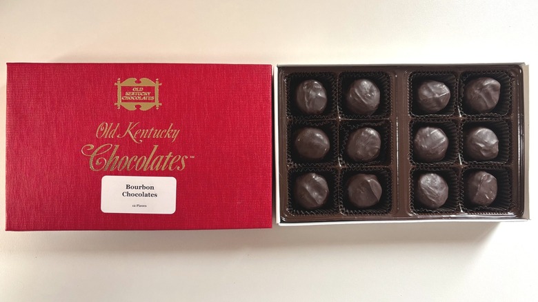 Box of Old Kentucky Chocolates bourbon balls next to red lid on white table