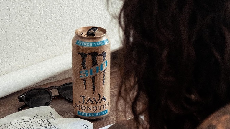 person drawing at desk with java monster can