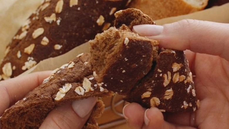 hands tearing a piece of brown bread