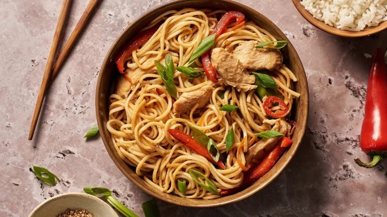 chinese noodles in bowl with chicken and bell peppers