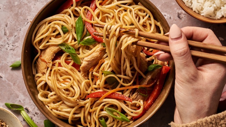 Chopstick picking up noodles from bowl