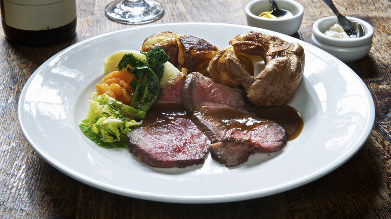 A British roast dinner with beef, Yorkshire puddings, vegetables, and gravy