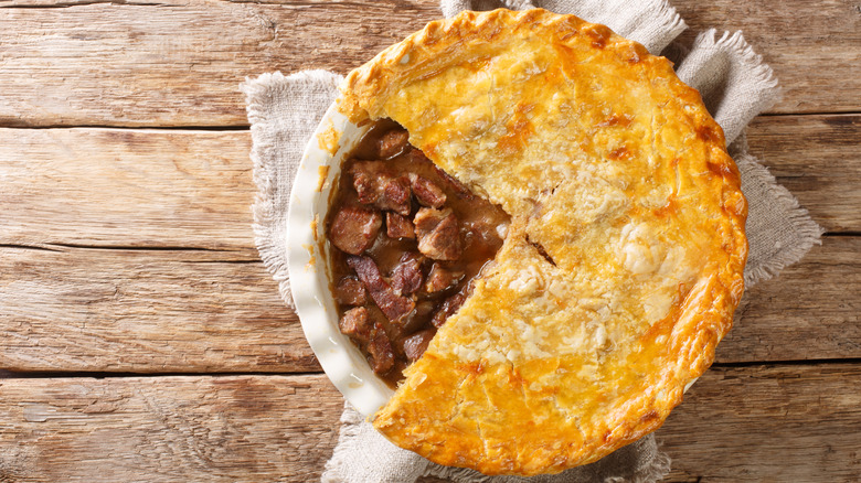 Steak and ale pie in dish with slice taken out