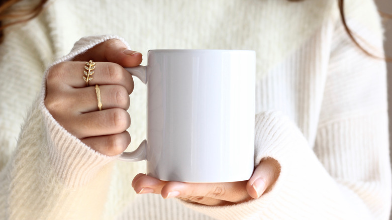 woman in sweater holding coffee mug