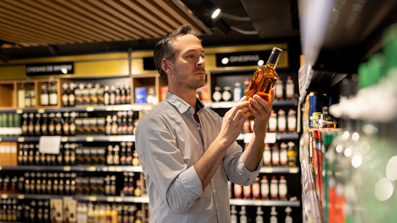 man looking at bottle of bourbon