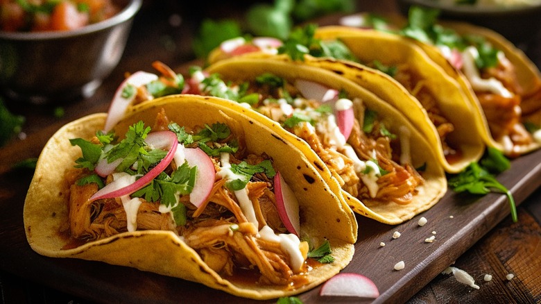 Four tacos on a wooden serving board