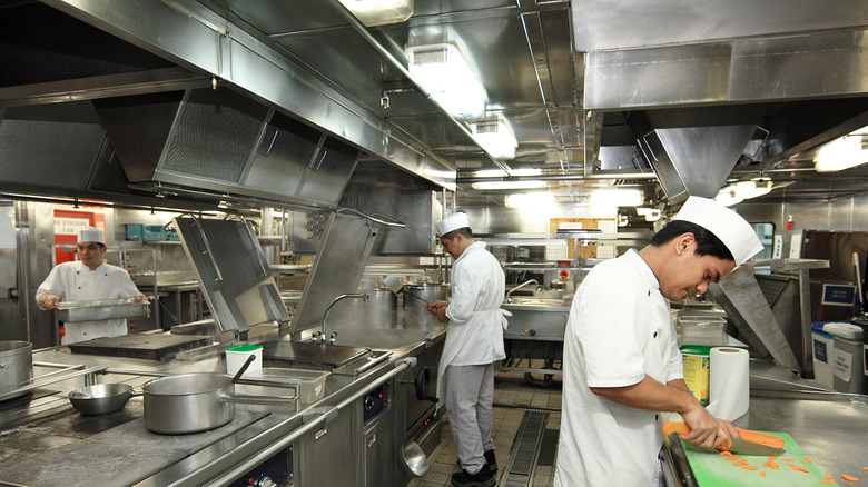 Three cruise ship chefs working in kitchen