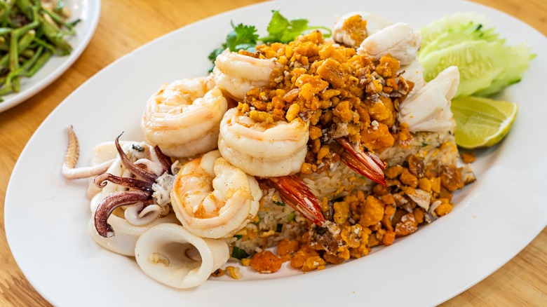 An overloaded plate of food containing seafood and rice