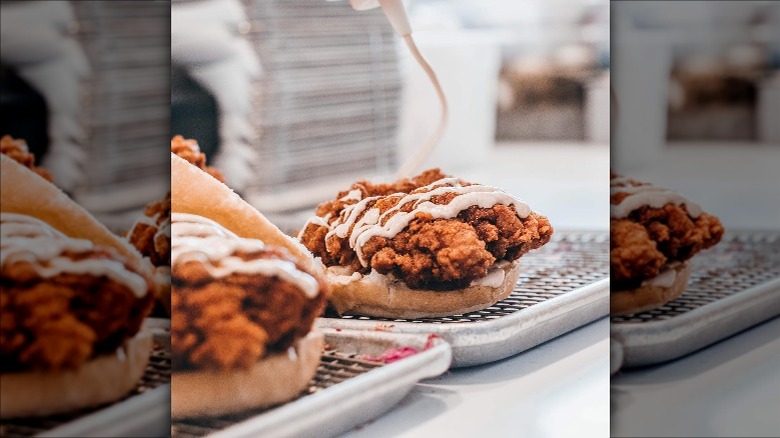 Pouring sauce on chicken sandwich