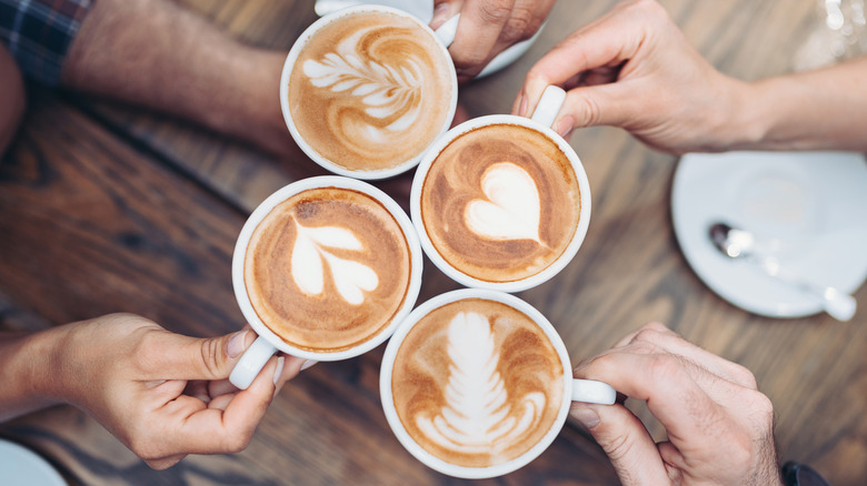 Four cups of lattes with different art patterns on them