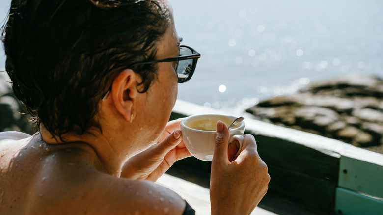 Person drinking a latte at a table near the ocean