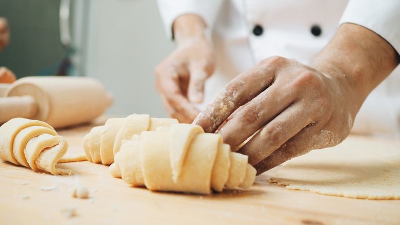 Baker rolling croissants on table