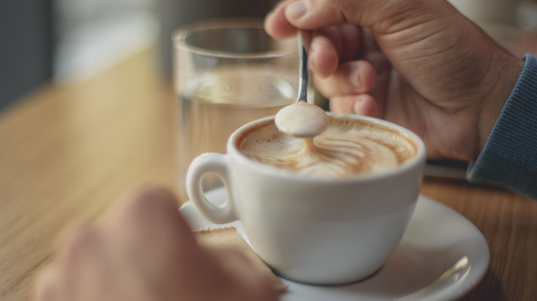 male hands stirring cappuccino 