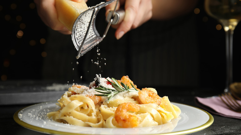 Grating cheese onto shrimp pasta dish