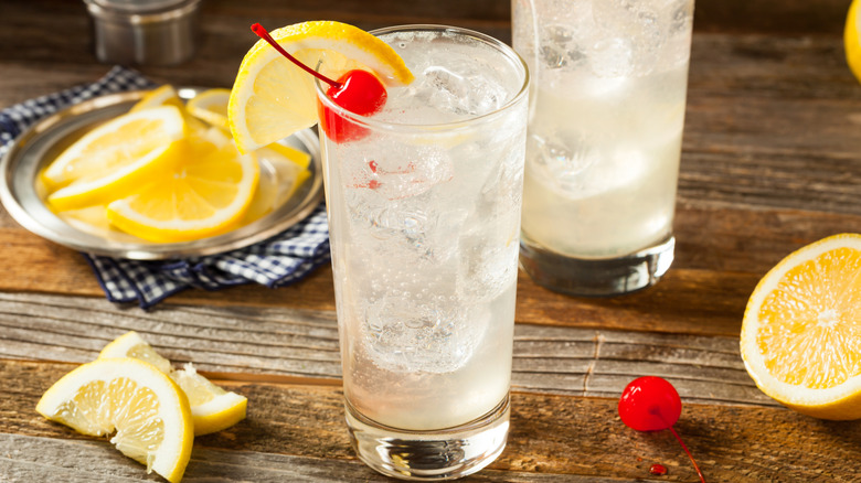 Tom Collins in a tall glass with ice, with lemon slices and cocktail cherries