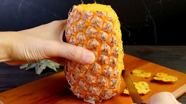 Hands cutting pineapple with knife