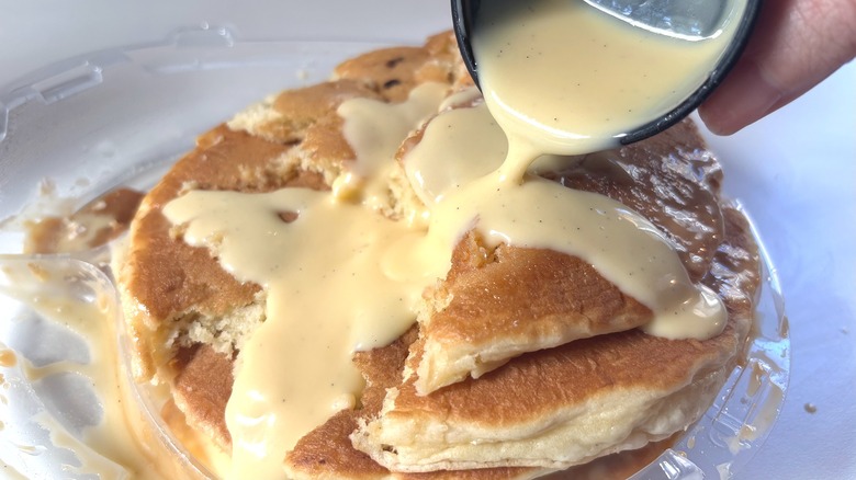 Pouring vanilla cream onto IHOP Cinn-A-Stack Pancakes