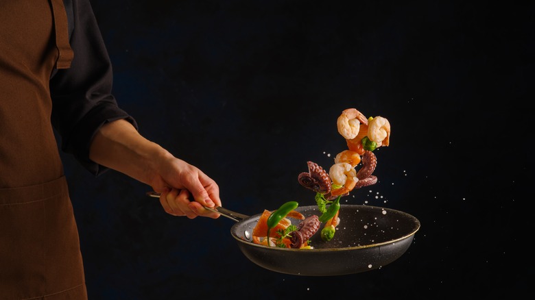 Chef sautéing mixed seafood items