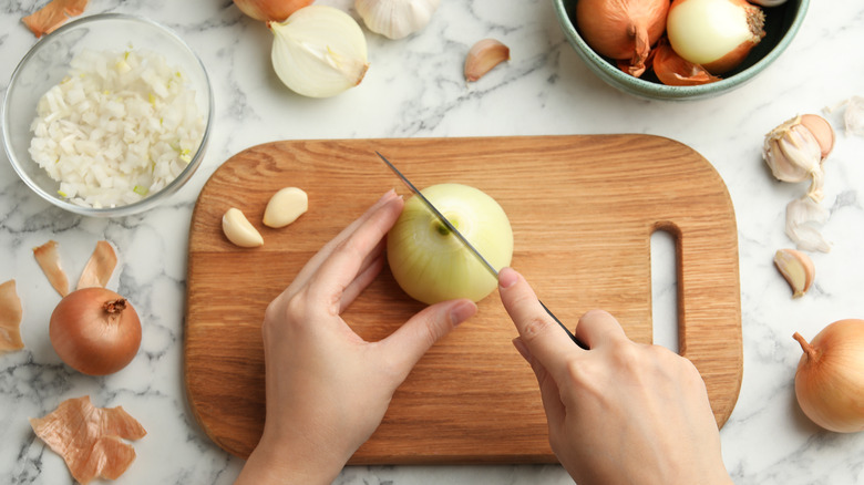 female hands slicing yellow onions