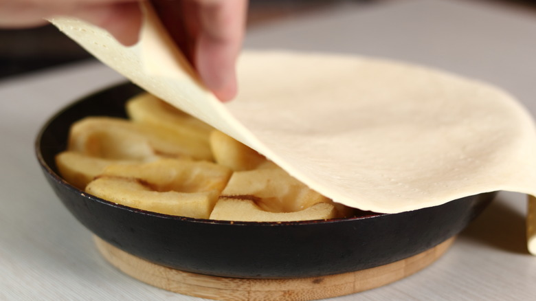 laying puff pastry over apples