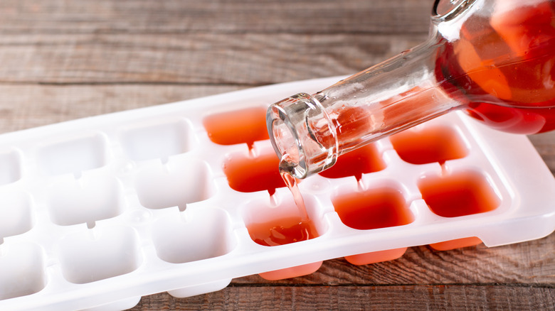 Pouring wine in ice cube tray on a wooden table