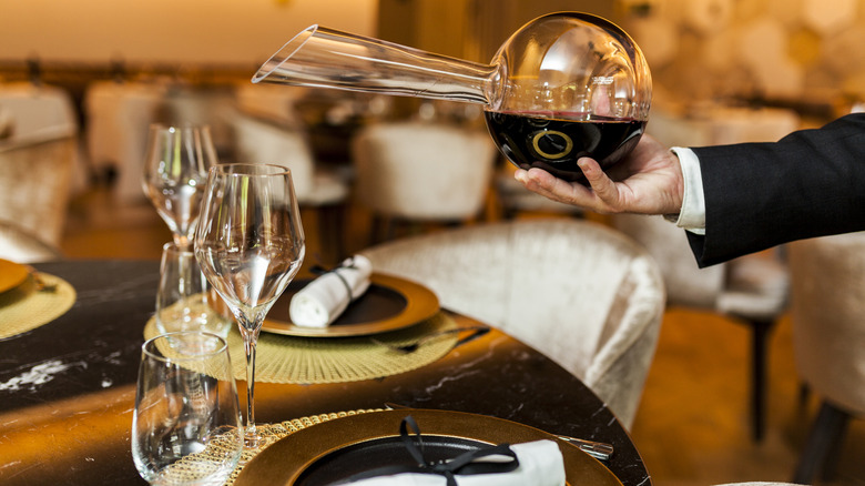 A sommelier pouring from a wine decanter