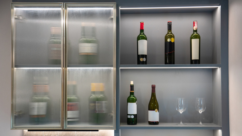 A modern kitchen featuring shelves with wine bottles