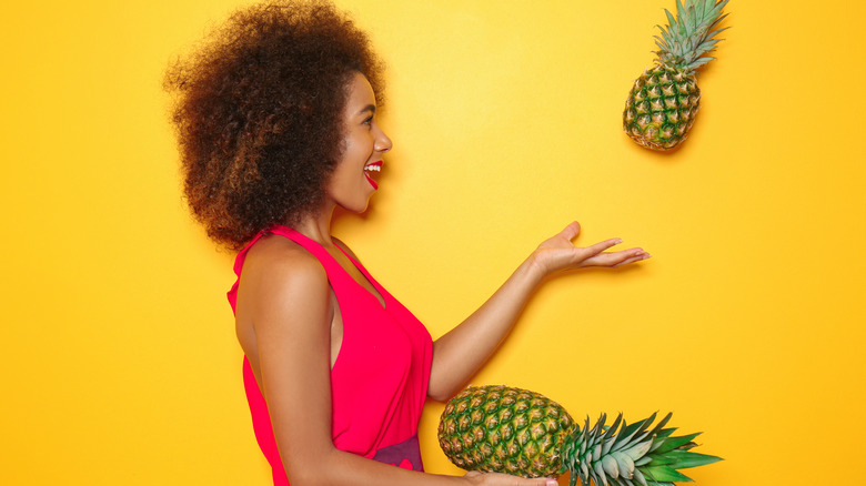 Woman tossing pineapple