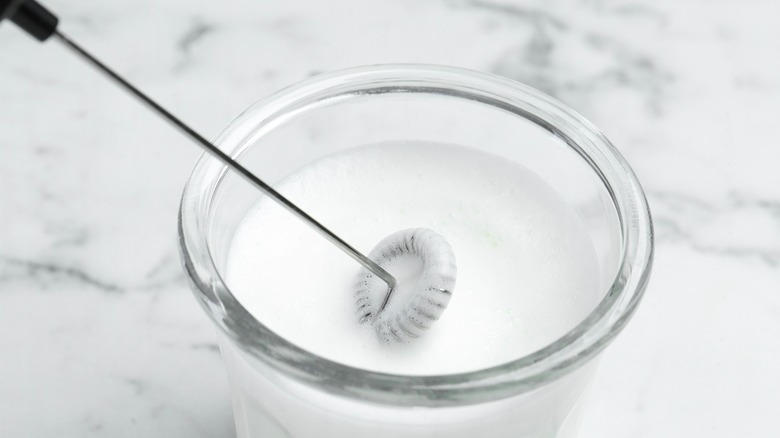 milk frother in small glass of milk