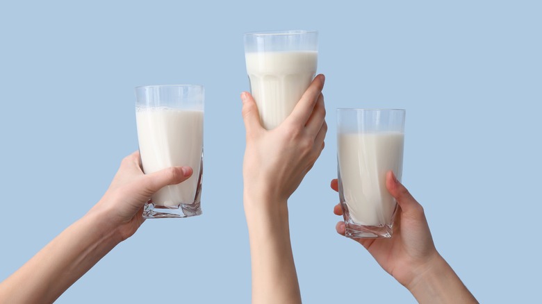 three hands holding milk glasses