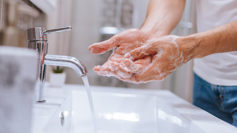 Hand washing with soap in bathroom 