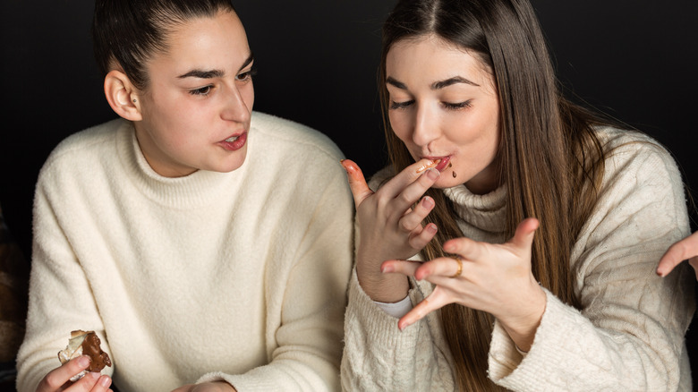 Two girls eating and licking fingers