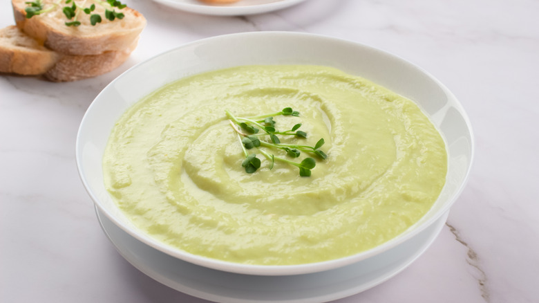 A bowl of chilled potato and leek soup with bread on the side