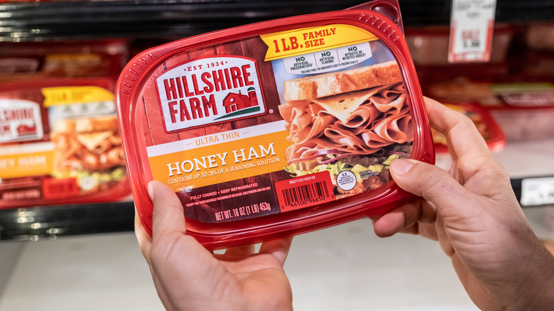 Hand holding Hillshire Farm sliced deli ham