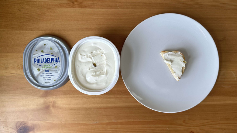 Spicy jalapeno cream cheese is shown on a bagel and in the container.