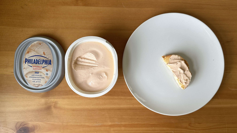 Smoked salmon cream cheese is shown on a bagel and in the container.