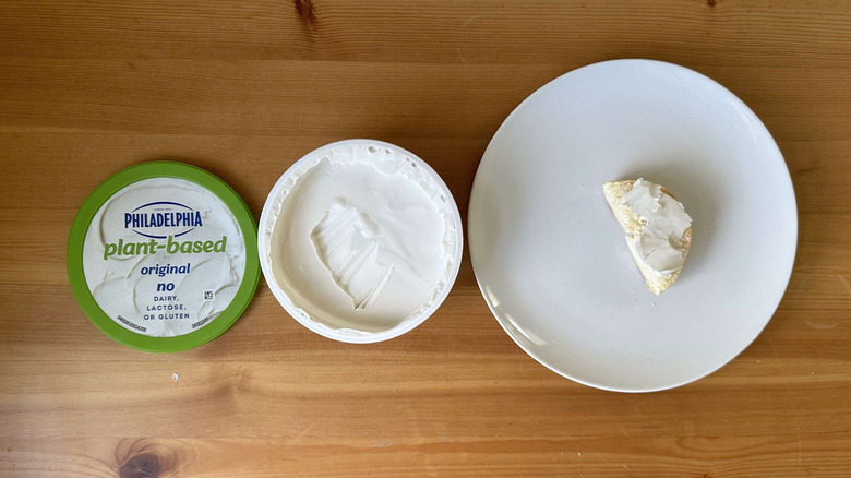 Plant based original cream cheese is shown on a bagel and in the container.