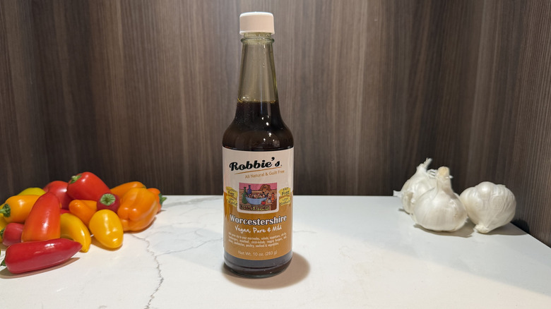 a bottle of Robbie's Worcestershire sauce with garlic bulbs and sweet peppers