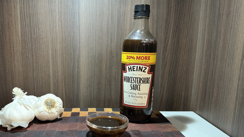 a bottle of Heinz Worcestershire sauce, a bowl of sauce, and three garlic bulbs
